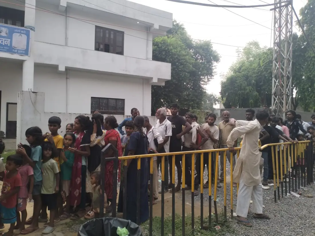 A long queue along the railing outside the hall, waiting for the meal