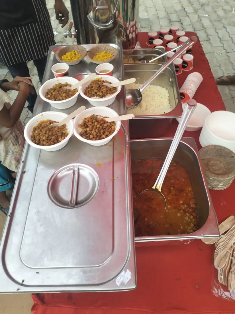 Bowls of chhole and rice laid out in trays on the serving table